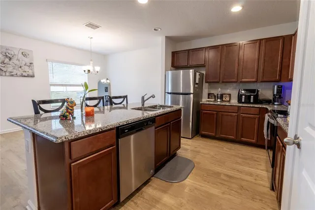 a kitchen with stainless steel appliances granite countertop a sink stove and refrigerator
