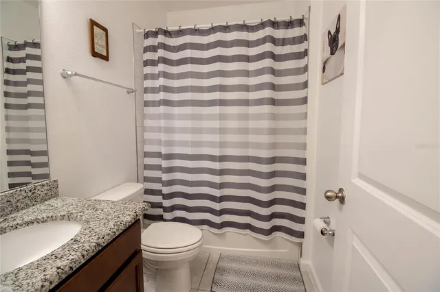 a bathroom with a granite countertop sink toilet and mirror