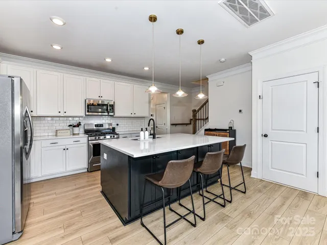 a kitchen with stainless steel appliances kitchen island granite countertop a refrigerator a sink dishwasher and a stove with wooden floor