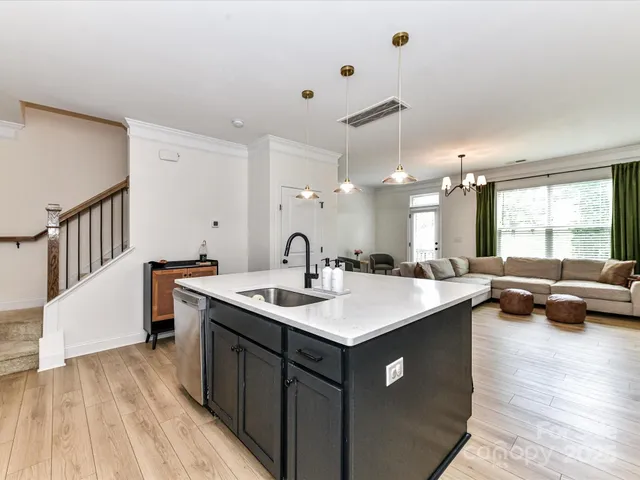 a kitchen with a sink a counter top space and living room view