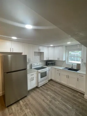 a kitchen with a white refrigerator a sink dishwasher with a dining table and chairs