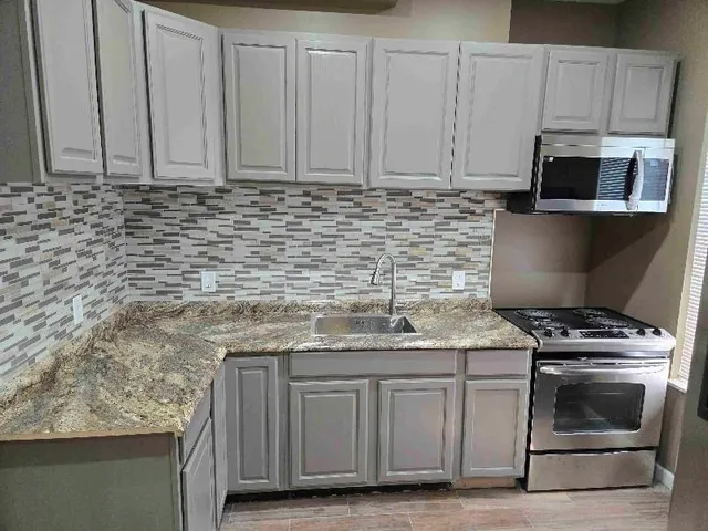 a kitchen with granite countertop a stove top oven microwave and cabinets