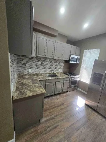 a kitchen with stainless steel appliances granite countertop a sink dishwasher a stove with wooden floor
