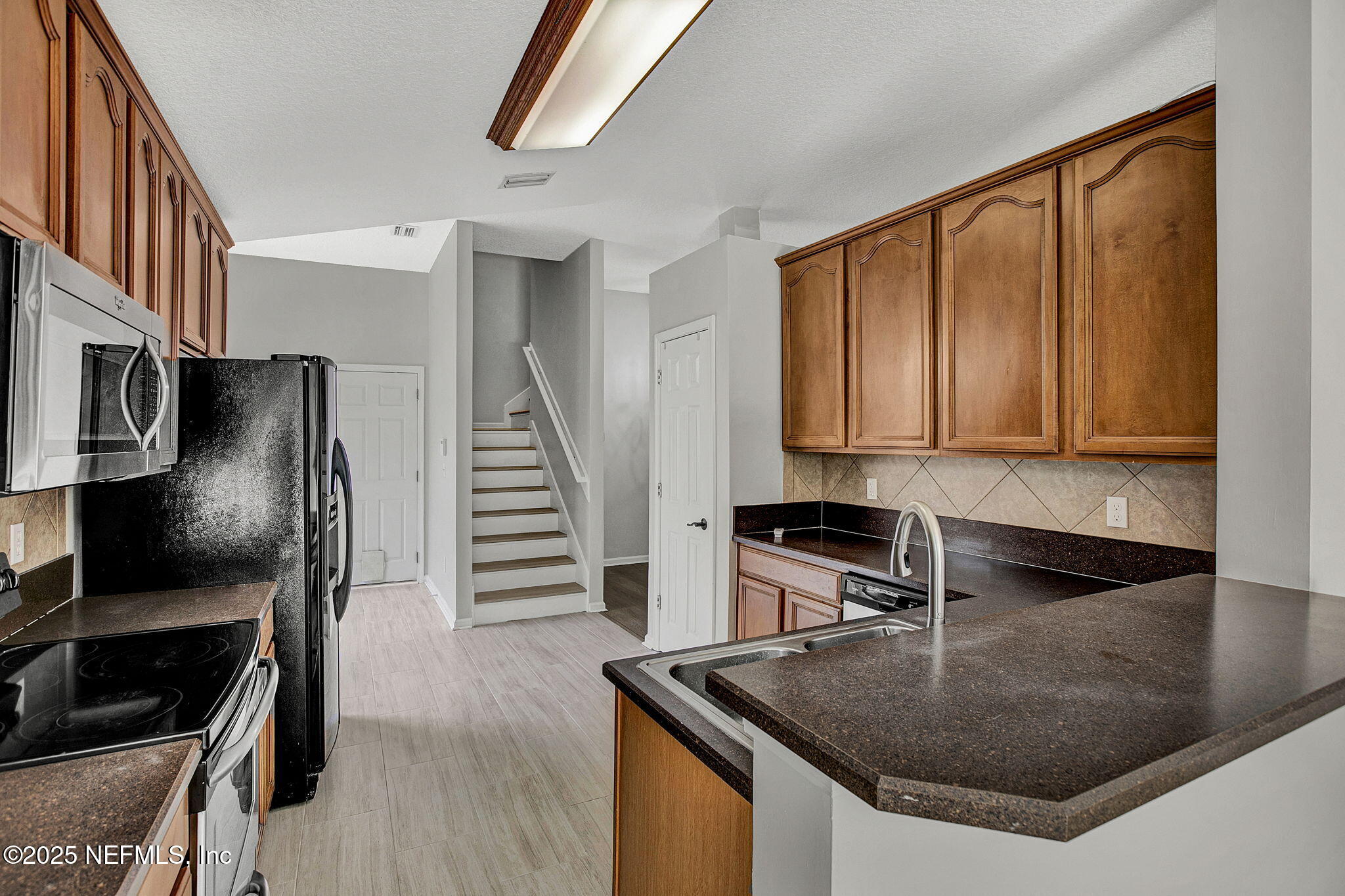 939 Silver Spring Court St. Augustine, FL 32092 - Photo 11 of 31 a kitchen with stainless steel appliances granite countertop a sink a microwave and wooden cabinets