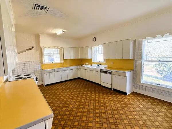a large white kitchen with a sink a stove and a window