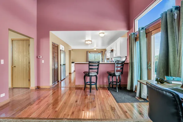 a kitchen with stainless steel appliances granite countertop a stove a refrigerator a sink a dining table and chairs with wooden floor