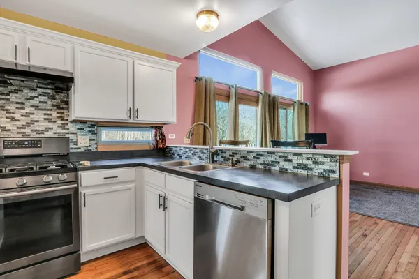 a kitchen with stainless steel appliances granite countertop a stove a sink and a microwave