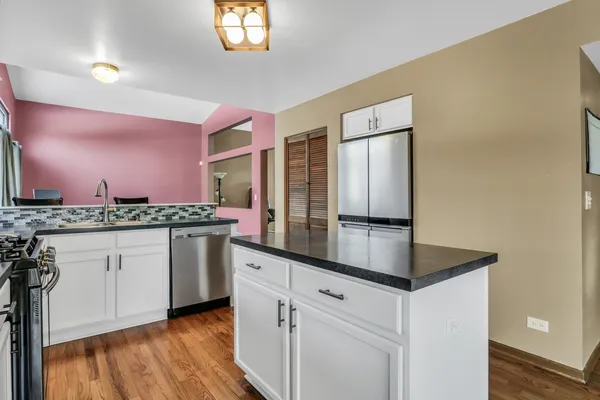 a kitchen with stainless steel appliances granite countertop a sink a stove and a wooden cabinets