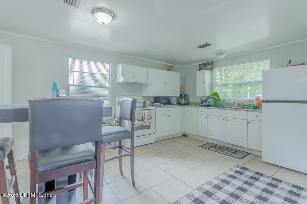 9042 7th Avenue Jacksonville, FL 32208 - Photo 9 of 22 a kitchen with a table chairs refrigerator and window