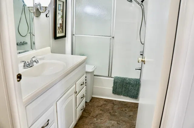 a bathroom with a granite countertop sink a mirror and shower