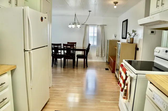 a kitchen with stainless steel appliances a refrigerator a stove a kitchen island a dining table and chairs