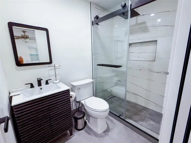 a bathroom with a sink toilet vanity and shower