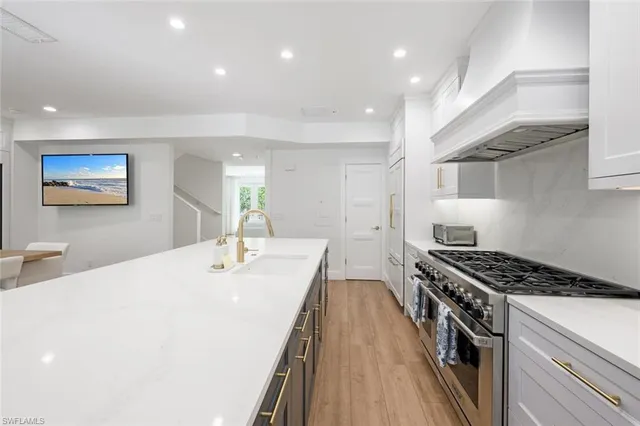 a kitchen with stainless steel appliances granite countertop hardwood floor sink stove dining table chairs and wooden floor