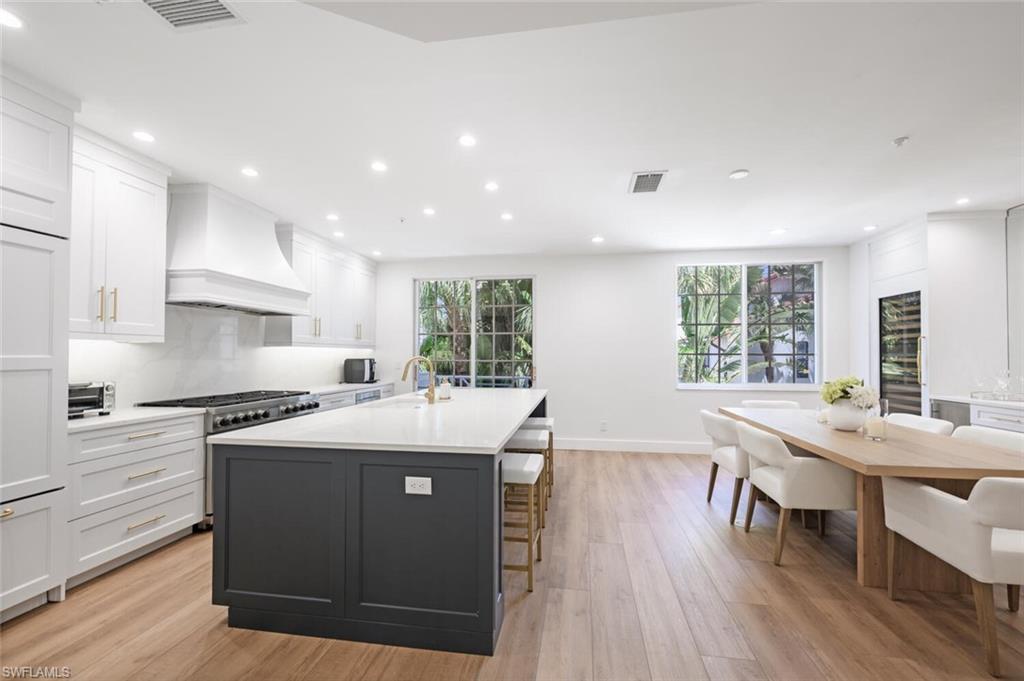 888 10th Street South, Unit 101 Naples, FL 34102 - Photo 13 of 44 a kitchen with stainless steel appliances granite countertop hardwood floor sink stove dining table chairs and wooden floor