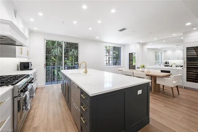 a kitchen with stainless steel appliances granite countertop a table chairs sink refrigerator and cabinets