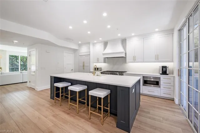 a kitchen with stainless steel appliances granite countertop a refrigerator a sink dishwasher a stove and a refrigerator with wooden floor