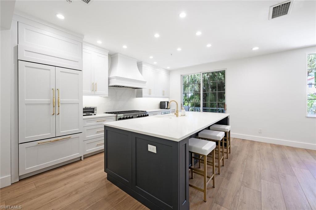888 10th Street South, Unit 101 Naples, FL 34102 - Photo 16 of 44 a kitchen with stainless steel appliances granite countertop a refrigerator a sink dishwasher a stove and a refrigerator with wooden floor
