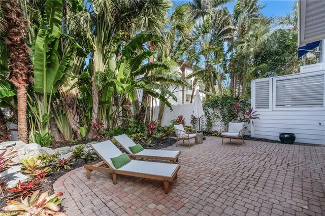 a view of a patio with table and chairs potted plants and a large tree