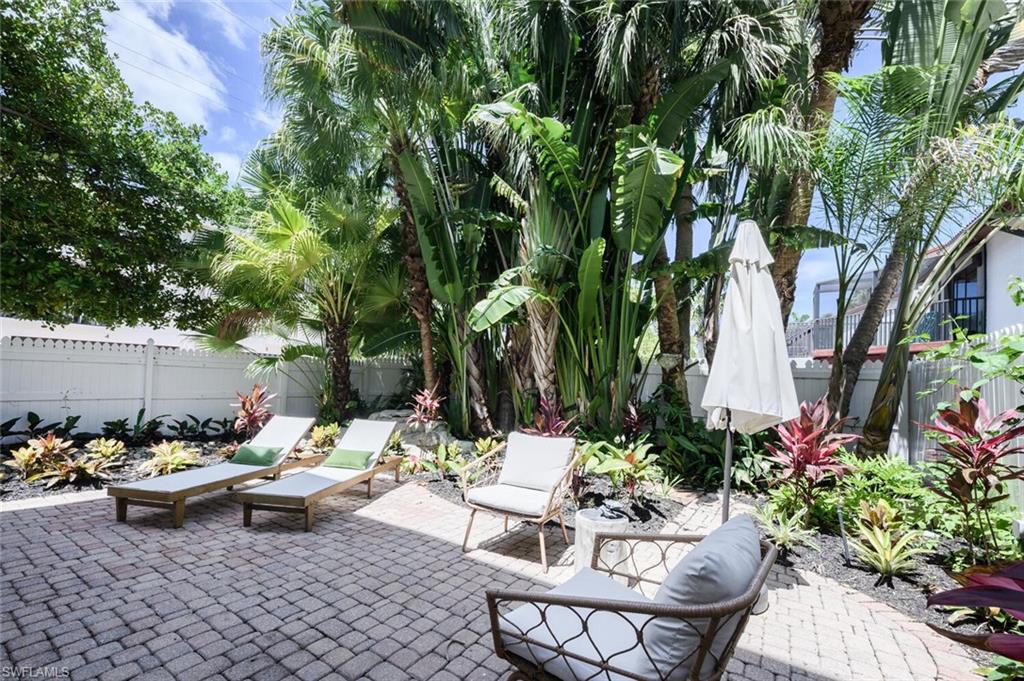 888 10th Street South, Unit 101 Naples, FL 34102 - Photo 43 of 44 a view of a patio with table and chairs potted plants and a large tree