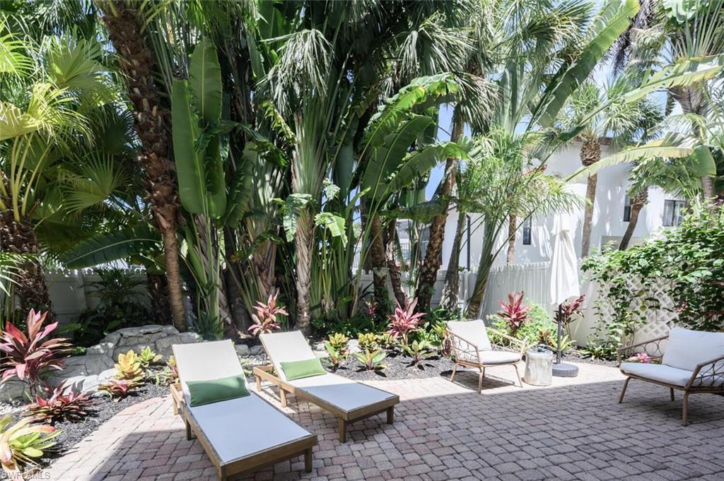 888 10th Street South, Unit 101 Naples, FL 34102 - Photo 44 of 44 a view of a backyard with couches potted plants and a large tree