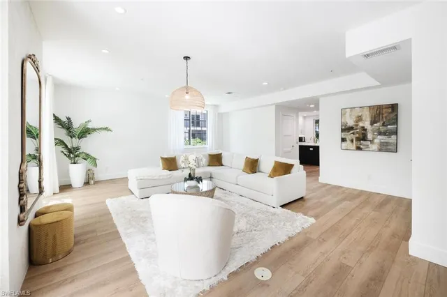 a living room with furniture kitchen view and a wooden floor
