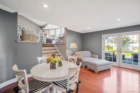 a living room with couches and a dining table with wooden floor