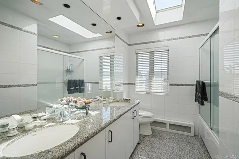 a bathroom with a granite countertop sink a toilet a mirror and shower