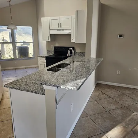 a kitchen with granite countertop a sink and a stove