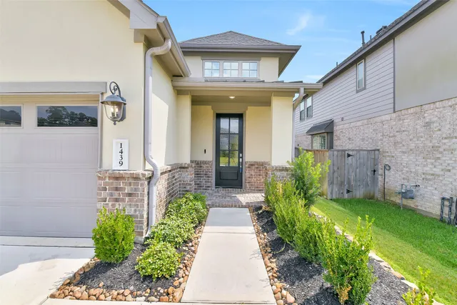 a view of a house with brick walls and a yard with plants