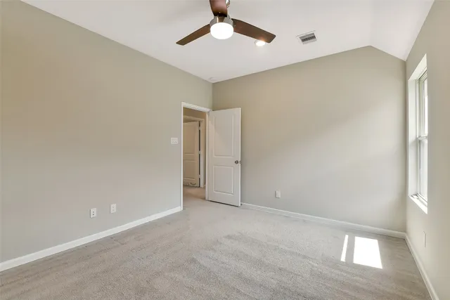 an empty room with windows and chandelier fan