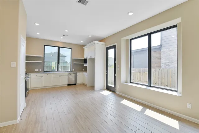 a view of an empty room with a window and wooden floor