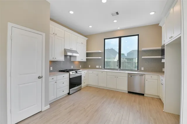 a large kitchen with granite countertop a stove top oven sink and cabinets