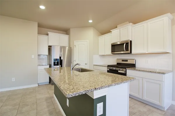a kitchen with kitchen island granite countertop a sink a stove counter space and cabinets