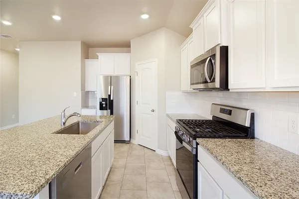 a kitchen with granite countertop a sink and refrigerator