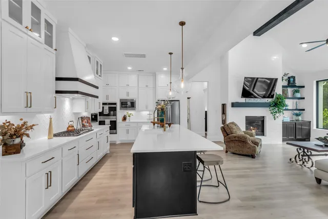 a large kitchen with stainless steel appliances kitchen island granite countertop a table chairs and a refrigerator