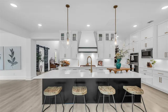 a kitchen with stainless steel appliances granite countertop a stove a refrigerator a sink a dining table and chairs with wooden floor