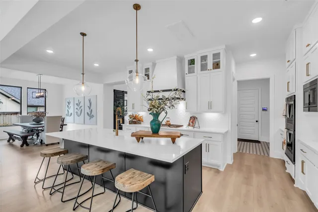 a room with stainless steel appliances kitchen island granite countertop a table chairs and a refrigerator