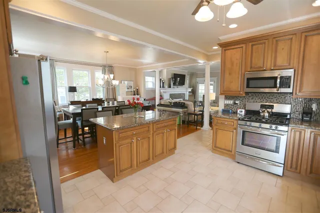 a kitchen with stainless steel appliances granite countertop a stove top oven a sink dishwasher a refrigerator and a dining table with kitchen view