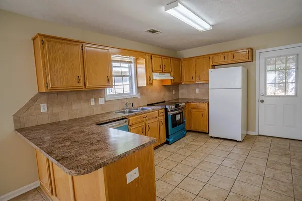 a kitchen with stainless steel appliances granite countertop a stove a sink dishwasher and a refrigerator