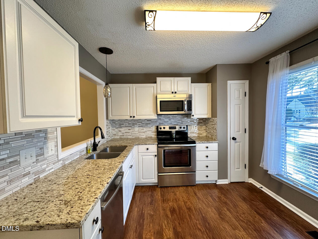 7020 Epping Forest Drive Raleigh, NC 27613 - Photo 3 of 24 a kitchen with granite countertop stainless steel appliances a stove sink and microwave