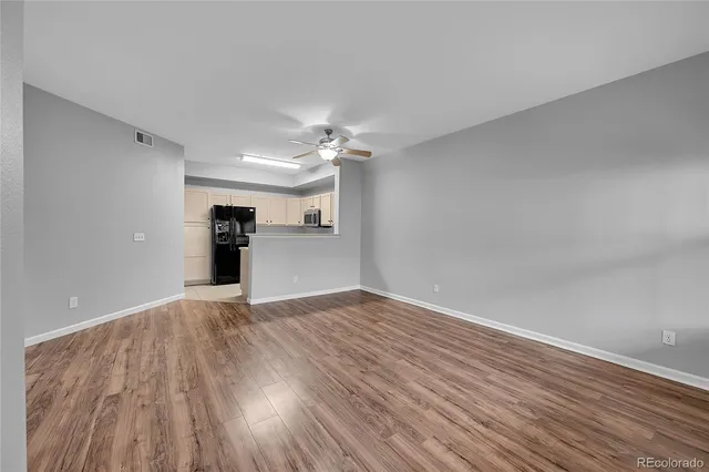 a view of empty room with wooden floor and ceiling fan