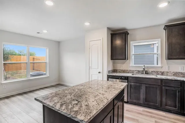 a kitchen with granite countertop kitchen island a sink stove and wooden floor