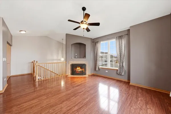 a view of an empty room with wooden floor fireplace and a window