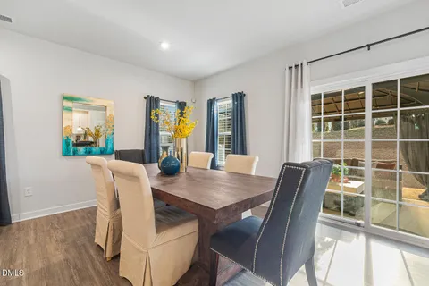 a kitchen with stainless steel appliances granite countertop a dining table chairs refrigerator and sink