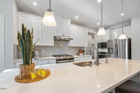 a kitchen with a white table chairs and wooden floor