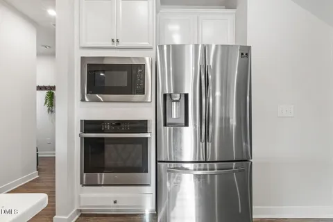 a kitchen with a dining table chairs refrigerator and wooden floor