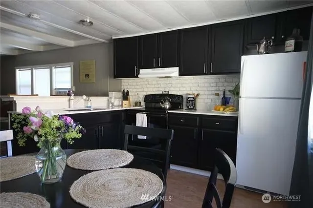 a kitchen with a refrigerator a stove a sink dishwasher and a dining table with wooden floor