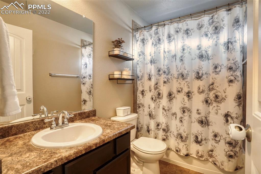 6729 Kearsarge Drive Colorado Springs, CO 80925 - Photo 12 of 22 a bathroom with a granite countertop sink toilet and a mirror
