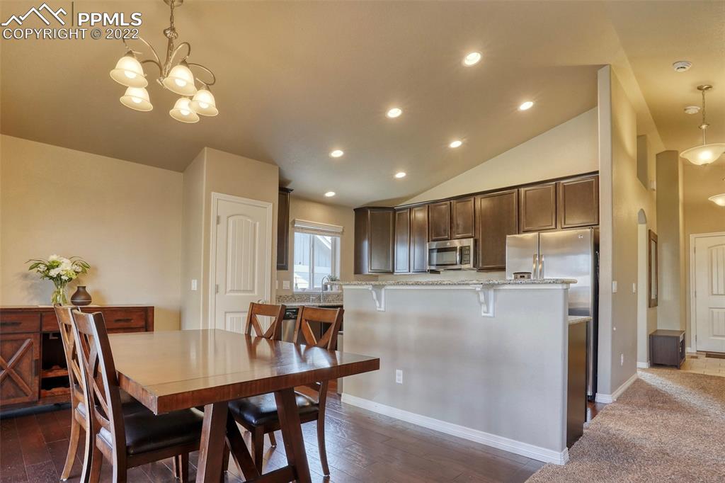 6729 Kearsarge Drive Colorado Springs, CO 80925 - Photo 4 of 22 a kitchen with kitchen island a dining table chairs stainless steel appliances and cabinets