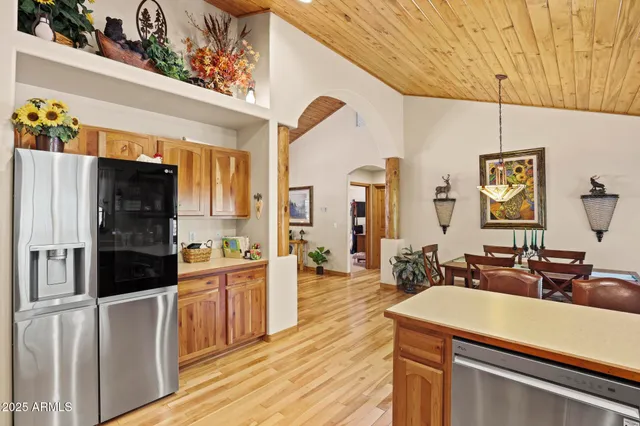 a kitchen with stainless steel appliances a stove a refrigerator a sink dishwasher and a dining table with wooden floor